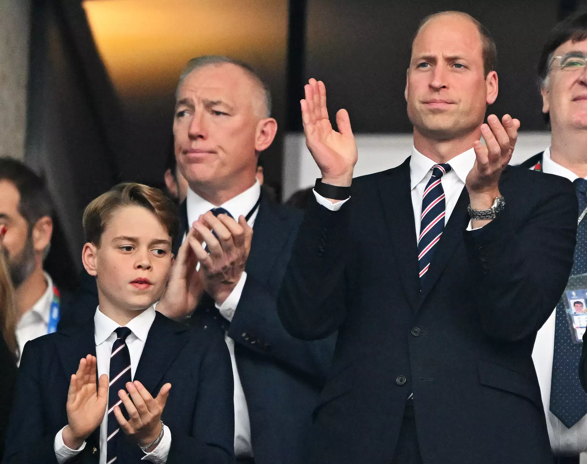 William Prince of Wales, and his son Prince George applaud in the stands before the start of the match.