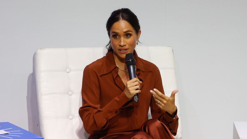 Meghan Markle sitting and speaking into a microphone